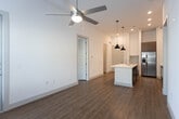 Located at 1321–1329 E Mockingbird Ln in Midland, Texas, this single-story unit showcases a contemporary design with clean lines and a neutral color palette throughout. The open-concept kitchen serves as the heart of the space, anchored by a large center island with a white quartz countertop and an undermount sink, illuminated by two industrial-style pendant lights. Cabinetry combines crisp white uppers with warm wood-toned lower cabinets, complemented by a subway tile backsplash and a full suite of stainless steel appliances, including a refrigerator, range, microwave, and dishwasher. The kitchen flows naturally into the living area, which receives natural light through large windows fitted with horizontal blinds and is equipped with a ceiling fan. Wood-look flooring runs consistently throughout the unit, adding warmth and visual continuity. The bedrooms are well-proportioned, bright, and airy, each with windows that bring in natural light. The bathroom features a wood-toned vanity with a white countertop, a framed mirror, and a tub-shower combination with tile surround. Additional storage is provided through a walk-in closet with built-in shelving and hanging rods, enhancing the unit's overall functionality.