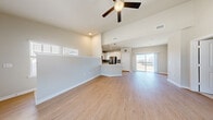 This thoughtfully designed single-floor residence combines modern aesthetics with functional living across a well-proportioned floor plan. The entrance welcomes you via a carpeted staircase with clean white walls, leading into the heart of the home.

The open-concept kitchen and living area serves as the centerpiece of the space, featuring striking vaulted ceilings and light-toned hardwood flooring throughout. The kitchen is outfitted with white shaker-style cabinetry, quartz countertops, a grey subway tile backsplash, and stainless steel appliances including a range, over-the-range microwave, and dishwasher. A peninsula provides additional prep space and visual separation from the living area, which is illuminated by natural light from sliding glass doors that lead to an outdoor balcony, as well as clerestory windows above.

The generously sized bedroom features plush carpet, vaulted ceilings, a ceiling fan, and a window with an exterior view. It connects seamlessly to a dedicated walk-in closet with wire shelving for ample storage, as well as the full bathroom. The bathroom is finished with hardwood-style flooring, a white vanity with light countertops, and a tub-shower combination with classic white subway tile surround.