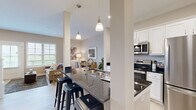 Located at 3451 Kells Way in Grove City, Ohio, this thoughtfully designed three-story home offers two bedrooms, two bathrooms, and a well-organized layout spread across three distinct levels. The entry level welcomes you through a bright, corridor-style entrance with light flooring, clean white trim, and a glass-paneled front door that draws in natural light.

The main living level serves as the heart of the home, where an open-concept kitchen and living area flow seamlessly together. The kitchen is highlighted by dark granite countertops, white shaker-style cabinetry, stainless steel appliances, and a peninsula with bar seating — ideal for casual dining or entertaining. Pendant lighting adds a polished touch overhead. The adjacent living room is generously proportioned, offering a relaxed, comfortable atmosphere with access to natural light from nearby windows. A dedicated laundry room on this level includes a full-size washer and dryer, utility sink, and built-in shelving.

The upper floor houses both bedrooms, each carpeted and finished with neutral tones. The primary bedroom is spacious and includes access to a walk-in closet with built-in rod shelving. Both bathrooms are clean and functional, featuring white vanities and wood-look flooring. The layout also includes a hallway connecting the upper-level rooms with ample closet storage throughout.