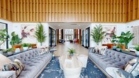 Located at 1425 Gallatin Pike N in Nashville, Tennessee, this striking single-floor community clubhouse offers a sophisticated and welcoming atmosphere defined by contemporary design and high-end finishes. The space makes an immediate impression with its soaring double-height ceilings, extensive vertical wood slat wall paneling, and intricate geometric parquet-style flooring that flows throughout the interior.

The grand lobby and lounge area serves as the heart of the space, anchored by plush tufted sofas, layered area rugs, and lush tropical greenery that adds warmth and vitality. Large floor-to-ceiling windows and glass entry doors flood the interior with abundant natural light while offering views of the surrounding outdoor environment.

A stylish bar and lounge area features a dramatic dark tile backsplash, dark stone countertops, pendant globe lighting, and a full row of modern bar seating—ideal for social gatherings. Adjacent areas provide flexible seating arrangements, including intimate booth-style nooks with teal upholstery and marble-top tables, as well as open co-working stations positioned near expansive windows.

Throughout the hallways and transition spaces, curated artwork and decorative wall hangings complement the overall design narrative. The cohesive blend of natural wood tones, deep navy accents, and gold hardware creates a refined yet approachable ambiance throughout this well-appointed Nashville clubhouse.