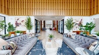Located at 1425 Gallatin Pike N in Nashville, Tennessee, this striking single-floor community clubhouse offers a sophisticated and welcoming atmosphere defined by contemporary design and high-end finishes. The space makes an immediate impression with its soaring double-height ceilings, extensive vertical wood slat wall paneling, and intricate geometric parquet-style flooring that flows throughout the interior.

The grand lobby and lounge area serves as the heart of the space, anchored by plush tufted sofas, layered area rugs, and lush tropical greenery that adds warmth and vitality. Large floor-to-ceiling windows and glass entry doors flood the interior with abundant natural light while offering views of the surrounding outdoor environment.

A stylish bar and lounge area features a dramatic dark tile backsplash, dark stone countertops, pendant globe lighting, and a full row of modern bar seating—ideal for social gatherings. Adjacent areas provide flexible seating arrangements, including intimate booth-style nooks with teal upholstery and marble-top tables, as well as open co-working stations positioned near expansive windows.

Throughout the hallways and transition spaces, curated artwork and decorative wall hangings complement the overall design narrative. The cohesive blend of natural wood tones, deep navy accents, and gold hardware creates a refined yet approachable ambiance throughout this well-appointed Nashville clubhouse.