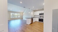 Located at 23 Station Rd in Brookfield, CT, this well-appointed two-story home offers 2 bedrooms and 2 bathrooms across two thoughtfully designed floors. The main level features an open-concept kitchen and living area bathed in natural light from large windows. The kitchen is outfitted with crisp white shaker cabinetry, dark granite countertops, a peninsula with a built-in sink, stylish pendant lighting, and a full suite of stainless steel appliances including a range, microwave, dishwasher, and refrigerator. Light hardwood flooring flows throughout both levels, complementing the home's clean, neutral palette. The living area benefits from vaulted ceilings and abundant natural light, creating an airy, open feel. A multi-paned French door provides additional brightness and outdoor access. The upper level hosts the bedrooms, including a generously sized primary suite with plush carpeting and crown molding. Both bathrooms are well-finished: one features a glass-enclosed walk-in shower and a white vanity, while the second includes a full tub-shower combo and a distinctive navy blue vanity with an LED-lit mirror. A hallway and closet complete the practical layout of this move-in-ready home.
