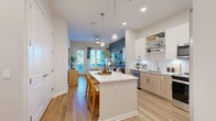 Located at 10139 Arise Loop in Orlando, FL, this well-appointed one-bedroom, one-bathroom residence offers a thoughtfully designed single-floor layout with a bright, modern aesthetic throughout. Light wood-tone flooring flows seamlessly across the entire space, lending warmth and visual continuity.

The open-concept kitchen, dining, and living area forms the heart of the home. The kitchen is equipped with stainless steel appliances — including a side-by-side refrigerator, range, and built-in microwave — complemented by two-tone cabinetry in white and light natural wood, white quartz countertops, a subway tile backsplash, and a central island with bar seating. Pendant lighting above the island adds a polished touch. The adjoining living room features a bold teal accent wall with floating shelves, large windows that invite abundant natural light, and direct access to the private balcony, which overlooks palm tree-lined outdoor surroundings.

The bedroom offers a comfortable retreat with a teal accent wall, a large window, and access to a generously sized walk-in closet with built-in wire shelving. The full bathroom features a soaking tub and shower combo, wood-tone vanity cabinetry, and clean white finishes. Additional highlights include in-unit laundry and two additional closets for ample storage.
