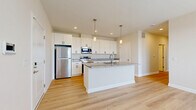 Located at 2150 Echo Dr in Sidney, Ohio, this well-appointed 2-bedroom, 2-bathroom residence offers a thoughtfully designed single-floor layout that blends modern style with everyday functionality. The open-concept living, dining, and kitchen area serves as the heart of the home, anchored by a striking kitchen featuring crisp white shaker cabinetry, speckled granite countertops, a large center island with an undermount sink, stainless steel appliances, and elegant pendant lighting overhead. Light hardwood flooring flows throughout the main living areas, enhancing the bright, airy ambiance. The living area opens directly to a private balcony through a glass-panel door, allowing natural light to pour in while offering outdoor views of the surrounding neighborhood. Both bedrooms are generously sized, with plush carpeting and large windows that fill the rooms with natural light. The primary bedroom includes dedicated closet space. Two full bathrooms echo the home's clean aesthetic with granite-topped vanities and hardwood-style flooring. Additional highlights include a dedicated laundry room, a utility room, three closets for ample storage, and a connecting hallway that ties the layout together seamlessly. The overall design is clean, contemporary, and move-in ready.