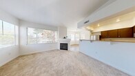 Located at 1350 W Horizon Ridge Pkwy in Henderson, NV, this two-story, 3-bedroom, 2-bathroom residence offers a well-organized and comfortable layout. The main living level features an open-concept design that seamlessly connects the living room, dining area, and kitchen. The living room is bright and airy, filled with natural light from large windows and anchored by a tiled fireplace with a clean white mantel. Soft carpet flooring adds warmth throughout the living spaces. The kitchen is well-appointed with dark cabinetry, granite-style countertops, stainless steel appliances including a refrigerator, gas range, microwave, and dishwasher, and wood-look flooring. A pass-through counter connects the kitchen to the dining area. The spacious primary bedroom features vaulted ceilings, plush carpet, a walk-in closet, and access to a private balcony overlooking the surrounding landscape. The primary bathroom includes a soaking tub, a separate glass-enclosed shower, and dark wood vanity. The secondary bathroom offers a combined tub/shower and matching vanity. Additional highlights include a dedicated laundry area, ample closet storage throughout, a staircase connecting both levels, and an attached garage with an automatic opener.