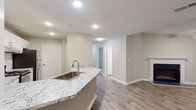 Located along Seasons Pkwy in Norcross, Georgia, this single-floor residence offers a thoughtfully designed layout with contemporary finishes throughout. The open-concept kitchen serves as a central highlight, featuring granite countertops, a subway tile backsplash, white shaker-style cabinetry with brushed nickel hardware, stainless steel appliances including a range and dishwasher, and a peninsula with an undermount sink — ideal for both cooking and casual dining. Wood-look flooring runs through the main living and hallway areas, creating a cohesive and easy-to-maintain aesthetic. A well-proportioned hallway connects the living spaces to multiple bedrooms, each finished with plush carpeting, neutral walls, and natural light from windows with blinds. At least one bedroom includes a walk-in closet with a rod system for added storage. The bathrooms are finished consistently with granite-topped vanities, white cabinetry, framed mirrors, and tub-shower combinations with tile surrounds. The overall color palette of warm neutrals and crisp whites lends the space a clean, move-in-ready feel. Textured ceilings and recessed lighting add subtle architectural character throughout this functional and comfortable Norcross residence.