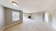 Located at 5180 Madison Ave in Okemos, Michigan, this well-appointed one-bedroom, one-bathroom residence offers a thoughtfully designed single-floor layout. The expansive living room serves as the heart of the home, featuring soft carpeting, neutral gray walls, and a classic fireplace as a focal point. Sliding glass doors flood the room with natural light and open directly onto a private balcony, offering pleasant outdoor views. A dedicated window further brightens the space, creating an open and airy atmosphere throughout. The galley-style kitchen is efficiently laid out with warm wood cabinetry lining both walls, a skylight overhead, durable vinyl flooring, and a full suite of appliances including a range, refrigerator, and dishwasher. A pass-through counter connects the kitchen to the living area. The bedroom is generously proportioned with plush carpet, a large window, and easy access to a dedicated closet. The full bathroom features a wood-toned vanity with a single sink, a well-lit mirror, and vinyl plank flooring. A separate laundry room with a full-size washer and dryer adds everyday convenience. Clean finishes and a neutral palette create a cohesive, move-in-ready environment throughout.