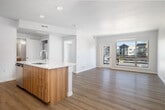 Located at 3852 E Warm Springs Ave in Boise, Idaho, this single-floor unit offers a thoughtfully designed open-concept layout with contemporary finishes and a bright, airy ambiance. Light wood-tone flooring flows throughout the main living areas, complementing the neutral white walls and creating a cohesive, modern aesthetic.

The kitchen is a standout feature, showcasing two-tone cabinetry with white upper cabinets and warm wood-grain lower cabinets, paired with a striking marble-look quartz countertop and matching island with an undermount sink. Stainless steel appliances, including a refrigerator, electric range, and over-the-range microwave, complete the space, while a clean subway tile backsplash adds a polished finishing touch.

The open living area connects seamlessly to a private balcony through a glass-paneled door, with a large picture window framing views of the surrounding Boise community. The bedroom features plush carpeting, a walk-in closet with built-in shelving, and a bright window providing natural light. The bathroom is finished with large-format neutral tile surrounding a soaking tub and shower combination, offering a clean and spa-like feel throughout.
