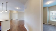 Located at 1200 Somerby Dr in Mobile, Alabama, this two-bedroom, one-bathroom residence offers a thoughtfully designed single-floor layout with generous living space. Rich, dark hardwood-style flooring flows through the main living and kitchen areas, creating a warm and cohesive aesthetic throughout.

The kitchen is a functional highlight, featuring warm wood cabinetry with a built-in wine rack, stone-toned countertops, a center island with pendant lighting overhead, and black appliances including a range, dishwasher, microwave, and refrigerator. An entrance area provides a welcoming transition into the home.

The primary bedroom is a comfortable retreat, outfitted with plush carpet, dual windows that invite natural light, a ceiling fan, and access to a closet. The second bedroom also features carpet flooring and a window with an outdoor view. The bathroom is well-equipped with a wide vanity, rich wood cabinetry, a large mirror, and stylish overhead lighting — all set atop hardwood-style flooring.

A standout feature of this residence is the covered outdoor porch, framed by white-painted columns and railings with a classic wood deck. The porch offers serene views of mature trees and lush greenery, providing a peaceful outdoor retreat. The neutral wall tones and consistent finishes throughout give the space a clean, move-in-ready appeal.