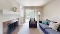 This single-floor residence offers a thoughtfully designed layout that balances comfort and functionality throughout. The living room serves as the heart of the home, anchored by a tile-surround fireplace with a classic mantel and complemented by a large sliding glass door fitted with vertical blinds that frame lush outdoor greenery, filling the space with natural light. Warm-toned carpet and neutral walls create an inviting, relaxed atmosphere.

The kitchen is outfitted with crisp white shaker-style cabinetry, sleek brushed nickel hardware, and elegant stone-look countertops that provide generous workspace. A built-in dishwasher adds everyday convenience to this clean, well-organized cooking space.

Adjacent to the kitchen, a cozy dining nook features a window with blinds that allows natural light to brighten mealtimes, creating an intimate setting for dining.

The bedroom is a serene retreat, carpeted for comfort and featuring a window with blinds that allows soft, natural light to filter through, set against a neutral color palette that promotes a calm ambiance.

The bathroom is finished with wood-look tile flooring, a white vanity with stone-look countertop, a framed mirror, and bright overhead lighting, contributing to the home's consistent, modern aesthetic. The water closet is separate, enhancing privacy and practicality.
