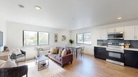 Located at 6515 Ridge Ave in Philadelphia's Roxborough neighborhood, this well-appointed 2-bedroom, 2-bathroom unit offers a thoughtfully designed single-floor layout with modern finishes throughout. The open-concept living, dining, and kitchen area serves as the heart of the home, featuring warm hardwood-style flooring, recessed lighting, and multiple large windows that flood the space with natural light and offer pleasant outdoor views of the surrounding neighborhood.

The kitchen is a standout feature, showcasing a striking two-tone design with dark navy lower cabinets, crisp white upper cabinets, a slate-blue subway tile backsplash, white quartz countertops, and a full suite of stainless steel appliances. The living area flows seamlessly from the kitchen, providing a comfortable and versatile space for both relaxing and entertaining.

The primary bedroom is a bright, calm retreat with a large window framing tree-lined views and ample room for a full furniture arrangement. The second bedroom is cozy and well-proportioned with clean white walls. Both bathrooms are stylishly finished — one features bold teal vertical tile in the tub surround, while the other offers a wood-toned vanity, tile flooring, and dark accent fixtures. A welcoming entry hallway completes this polished and functional home.