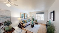 This single-floor residence offers a thoughtfully arranged layout connecting several distinct living areas. The living room serves as the heart of the home, featuring large windows dressed with valance treatments that admit generous natural light, smooth ceilings, and a transition from plush carpet to hardwood-style flooring. The space comfortably accommodates a full seating arrangement, with a glass-top coffee table anchoring the room.

The kitchen is equipped with light wood cabinetry, granite-toned countertops, and white appliances including a refrigerator, range, microwave, and dishwasher. Hardwood-style flooring continues throughout, and overhead fluorescent lighting keeps the workspace well-lit.

The bedroom offers carpeted flooring, a window with decorative curtain panels, and a sliding-door closet providing accessible storage. The room is generously proportioned to accommodate large furniture pieces.

The bathroom features a single-sink vanity with granite-toned countertops, light wood cabinetry beneath, a large mirror above the sink, and neutral wall tones that give the room a clean, functional appearance.

Throughout the residence, a consistent neutral color palette with warm wood accents creates a cohesive and welcoming ambiance.