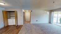 Located at 11328 SE Kent Kangley Rd in Kent, Washington, this ground-floor unit offers a well-organized, single-level layout designed for comfortable everyday living. The living area is generously sized, featuring plush wall-to-wall carpeting, a wood-burning fireplace as a central focal point, and a sliding glass door that fills the space with natural light and provides direct outdoor access to surrounding greenery. A separate entry door with wood-style flooring transitions smoothly into the carpeted living space.

The galley-style kitchen is efficiently laid out with warm wood-toned cabinetry, ample upper and lower storage, white countertops, and wood-style flooring. It is equipped with a full suite of white appliances including a range, refrigerator, and dishwasher, along with a window that brings in additional natural light.

A dedicated hallway leads to the bedroom, which is a comfortable, carpeted room featuring a window with blinds and a baseboard heating unit. The full bathroom includes wood-style flooring, a combined tub and shower with grab bars, a vanity with mirror, and clean, neutral finishes throughout.

A notable convenience is the in-unit laundry area, visible from the main living space, which includes a washer and dryer. Textured ceilings are consistent throughout the unit, and wall-mounted heating units provide additional climate control.