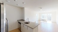 This 2-bedroom, 2-bathroom residence at 120 N Pearl St in Port Chester, NY offers a thoughtfully designed, single-floor layout with a clean, contemporary aesthetic. The open-concept living and dining area is bathed in natural light from large windows that frame views of the surrounding Port Chester streetscape, and features warm-toned hardwood-style flooring that flows seamlessly throughout the home. The modern kitchen is equipped with a full suite of stainless steel appliances—including a French door refrigerator, electric range, and microwave—complemented by dark upper cabinetry, light lower cabinetry, and a peninsula with a quartz countertop and undermount sink, ideal for both cooking and casual dining. Each bedroom is generously sized, featuring hardwood-style flooring, ample closet space, and large windows that invite natural light. The primary bathroom offers a sleek, spa-inspired feel with a walk-in shower, large-format neutral tile, a dark vanity with dual undermount sinks, and backlit mirrors. The second bathroom features a full soaking tub and shower combination with coordinating tile. Throughout, the residence maintains a bright, neutral palette that creates a welcoming and versatile living environment.