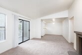 This single-floor residence offers a thoughtfully organized layout with a neutral, move-in-ready aesthetic throughout. The main living area is generously proportioned, featuring plush carpeting underfoot and a ceiling fan overhead. A structural beam delineates the space, creating distinct zones within the open floor plan. Sliding glass doors provide direct access to a private balcony, allowing natural light to fill the room while offering pleasant outdoor views of surrounding greenery. An adjacent window further enhances the bright, airy atmosphere.

The kitchen is practical and well-appointed, featuring white cabinetry, laminate countertops, a stainless steel double-basin sink, and a dishwasher. A large window above the sink frames lush tree views, making the space feel connected to the outdoors. The flooring here transitions to a wood-look surface, providing a clean contrast to the carpeted areas.

The bedroom is a comfortable, carpeted retreat with a sliding-door closet and a ceiling light fixture. A baseboard heater beneath the window ensures year-round comfort. The full bathroom is clean and functional, complete with a single-sink vanity topped with a large mirror, a toilet, and a tub-shower combination. A fireplace noted in the floor plan adds a welcoming focal point to the living space. The overall ambiance is calm, clean, and practical.