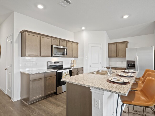 Rich brown cabinetry, chic subway title backsplash, and stunning granite countertops. - 6113 Bracken Dr