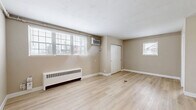 Located at 2885 Minto Ave in Cincinnati, OH, this efficiently designed single-floor unit offers a practical and comfortable layout. The living room is a bright, open space featuring light-toned luxury vinyl plank flooring, neutral beige walls, and clean white baseboards. Multiple windows fitted with horizontal blinds allow natural light to fill the room, while a wall-mounted air conditioning unit and a baseboard radiator provide year-round climate control. A sliding-door closet offers convenient built-in storage within the living area. The kitchen is neatly tucked into its own defined space, showcasing white cabinetry, warm wood-toned tile backsplash, stainless steel appliances including a range and refrigerator, and a gold-finish faucet — combining functionality with modern style. A flush-mount globe light fixture adds a subtle design touch overhead. The bathroom features floor-to-ceiling rectangular white tile surrounding a soaking tub, with a frosted window providing natural light and privacy. Three closets throughout the unit offer ample storage. The consistent flooring, cohesive neutral color palette, and updated finishes give the space a clean, move-in-ready feel.