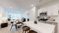 Located at 72 Eagle Rock Ave in East Hanover, NJ, this well-designed 3-bedroom, 2-bathroom residence offers a thoughtfully laid-out single-floor plan with a clean, modern aesthetic. The open-concept kitchen and dining area serves as the heart of the home, featuring white shaker cabinetry, stainless steel appliances including a gas range, built-in microwave, and French door refrigerator, all complemented by bright quartz countertops and light wood-tone flooring that flows throughout the space. A large kitchen island with bar seating connects seamlessly to the dining and living areas, making it ideal for entertaining. The living room is bright and welcoming, with a wide bank of windows that invite natural light and views of the outdoors. The primary bedroom is a comfortable retreat, featuring sliding glass doors that open to a private outdoor patio. Additional bedrooms are well-proportioned with thoughtful storage solutions, including a dedicated walk-in closet with wire shelving. Both bathrooms are finished in a clean, neutral palette with white vanities, quartz countertops, and tile flooring. A full walk-in shower is featured in the primary bath. Recessed lighting, light hardwood-style flooring, and crisp white walls give the entire residence a bright, cohesive, and contemporary feel.