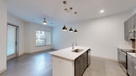 Located at 2814 Race St in Fort Worth, TX, this thoughtfully designed one-bedroom, one-bathroom residence offers a contemporary living experience across a well-utilized single floor. Polished concrete floors run throughout, lending a sleek, modern aesthetic that ties each room together seamlessly.

The open-concept kitchen is a standout feature, showcasing gray shaker cabinetry, a striking exposed brick backsplash, white quartz countertops, and stainless steel appliances. A central island with an undermount sink and pendant lighting serves as both a functional workspace and a natural gathering point, flowing effortlessly into the living area. The living space is brightened by natural light through large windows and a glass door, complemented by a ceiling fan overhead.

The bedroom is a comfortable, well-proportioned retreat with clean white walls and polished concrete flooring, accompanied by a generous walk-in closet outfitted with multi-tier wire shelving for ample storage. The bathroom features gray vanity cabinetry matching the kitchen, a wide mirror with vanity lighting, white quartz counters, wood-look tile flooring, and a tiled soaking tub and shower combination.

A dedicated laundry room houses a full-size Samsung washer and dryer. The unit also opens to a private patio with iron fencing, overlooking a landscaped courtyard with mature trees.
