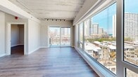 Located in Chicago's vibrant Uptown neighborhood, this 2-bedroom, 2-bathroom unit offers a distinctive industrial-loft aesthetic defined by exposed concrete ceilings, structural beams, and track lighting throughout. The open-concept living area is anchored by a wall of floor-to-ceiling windows and sliding glass doors that flood the space with natural light while framing expansive city skyline views and access to a private balcony. Wide-plank hardwood flooring runs throughout, lending warmth that balances the raw industrial elements above. The kitchen is well-appointed with white shaker cabinetry, a white subway tile backsplash, dark granite countertops, stainless steel appliances, and a central island that provides additional prep space and casual seating. Both bedrooms feature exposed concrete ceilings and hardwood floors, with the primary bedroom offering generous proportions and a window with outdoor views. The hallways include built-in storage with louvered-door cabinetry for added functionality. Both bathrooms are finished to a high standard, showcasing large-format marble-style tile surrounds, soaking tubs with combination shower fixtures, dark granite vanity tops, undermount sinks, and polished tile flooring, creating a clean and refined aesthetic throughout.