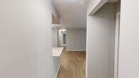 This single-floor, 3-bedroom, 2-bathroom residence offers a thoughtfully designed layout that maximizes functionality and comfort. The living room serves as the heart of the home, featuring warm wood-look luxury vinyl flooring and a large sliding glass door fitted with vertical blinds that floods the space with natural light. Neutral gray walls throughout create a clean, cohesive aesthetic.

The galley-style kitchen is well-equipped with crisp white shaker cabinetry, brushed nickel hardware, white quartz countertops, a subway tile backsplash, and stainless steel appliances. A dedicated laundry room is conveniently accessible directly from the kitchen and houses a full-size washer and dryer.

The three bedrooms are carpeted for comfort, each featuring neutral tones and ample natural light from large windows with blinds. The primary bedroom offers generous proportions and includes a closet with built-in shelving. Two closets throughout the unit provide additional storage. The two bathrooms are finished with wood-look flooring, white vanities with light countertops, and brushed nickel fixtures. Two hallways connect the living areas to the private bedroom wing, ensuring a smooth and practical flow throughout the residence.