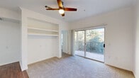 This well-appointed 2-bedroom, 2-bathroom single-floor residence in Fort Worth, TX, offers a thoughtfully designed layout with a welcoming entrance and a hallway connecting the key living spaces. The open living room serves as the heart of the home, showcasing rich hardwood-style flooring, crown molding, a ceiling fan, and a classic white-mantled fireplace flanked by built-in shelving — ideal for display or storage. Large French doors with transom windows flood the space with natural light and provide outdoor access. The kitchen is equipped with stainless steel appliances, including a range, microwave, dishwasher, and refrigerator, complemented by granite countertops, a dark subway tile backsplash, and crisp white shaker cabinetry. Both bedrooms feature plush wall-to-wall carpeting, ceiling fans, and windows that bring in ample natural light, with the primary bedroom offering direct outdoor access via a private door. Three closets provide generous storage throughout. The bathrooms are finished with granite-topped white vanities and hardwood-style flooring. The exterior features a stone perimeter wall with iron fencing, adding character to the outdoor surroundings.