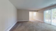 This single-floor unit is thoughtfully laid out across a functional floor plan visible in the 3D overview. The living area is generously proportioned, finished with neutral-toned carpet and warm beige walls, and connects openly to an adjacent room, creating a flowing, flexible space. Sliding glass doors allow abundant natural light and provide direct access to an outdoor area with views of surrounding greenery.

The kitchen is well-appointed with white shaker-style cabinetry, stone-look countertops, a stainless steel refrigerator, range, and built-in microwave, complemented by light hardwood-style flooring and a window that brightens the workspace.

The bedrooms are carpeted and finished consistently with the rest of the unit in neutral tones and white trim. One bedroom features a standard closet with paneled doors, while another benefits from dual windows that invite natural light and outdoor views. A third bedroom also captures natural light through multiple windows.

The bathroom features wood-look tile flooring, white subway tile surrounding a full soaking tub, and a small privacy window. Throughout the unit, clean white baseboards, neutral walls, and consistent finishes contribute to a cohesive, move-in-ready aesthetic.