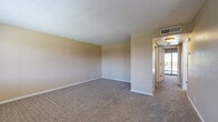 This single-story residence offers a practical and well-organized floor plan across two bedrooms, a combined kitchen and living area, a hallway, and a closet. Warm neutral tones and clean white baseboards are consistent throughout, creating a cohesive and inviting atmosphere.

The open kitchen and living area serves as the heart of the home. The kitchen features warm wood-toned cabinetry, white appliances including a refrigerator, microwave, and electric range, and durable laminate wood flooring. A ceiling fan with integrated lighting and a window with blinds allow for ventilation and natural light. The adjoining living area transitions to plush carpeting and includes a front entry door alongside a large window that frames outdoor views.

The primary bedroom is a generously sized retreat with plush carpet, a ceiling fan, and a sliding glass door leading to a private balcony with outdoor views. Full-length mirrored sliding closet doors enhance the sense of space. An additional walk-in closet provides ample shelving and hanging storage. The second bedroom also features laminate wood flooring, a ceiling fan, and a bright window with exterior views. A hallway connects the main living spaces, completing this efficiently designed and move-in ready home.