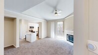 Located at 8025 Ohio Dr in Plano, TX, this well-appointed 2-bedroom, 3-bathroom single-floor residence offers a thoughtfully designed layout with a welcoming entrance that leads into a spacious living area. The living room is highlighted by a classic white-mantled fireplace, a ceiling fan, crown molding, and a glass door that opens to a private balcony overlooking mature trees, allowing for abundant natural light. The kitchen features white shaker cabinetry, white quartz countertops, a beige subway tile backsplash, stainless steel appliances including a dishwasher, and a central island with seating — all complemented by wood-look flooring and a natural light-filled window. Both bedrooms are carpeted and include ceiling fans, with the primary bedroom offering a walk-in closet with wire shelving and an en-suite bathroom complete with a soaking tub, white tile surround, and wood-look flooring. A second walk-in closet serves the additional bedroom. The three bathrooms are clean and functional, each featuring soaking tubs. An in-unit laundry area provides added convenience. Neutral tones and carpet throughout create a cohesive, comfortable ambiance.