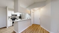 This single-floor residence is designed with a clean, neutral aesthetic throughout, featuring wood-look flooring and light gray walls that create a cohesive, modern feel. The entry foyer opens directly into the living area and provides immediate access to a louvered closet, offering convenient storage from the moment you step inside.

The kitchen is efficiently laid out with white cabinetry, light countertops, and a full suite of stainless steel appliances, including an electric range, over-the-range microwave, refrigerator, and dishwasher. A peninsula counter separates the kitchen from the adjacent living space, providing both a casual dining surface and a natural visual boundary.

Two bedrooms each feature wood-look flooring, ceiling fans with integrated lighting, and windows overlooking lush outdoor greenery, allowing natural light to fill both rooms. The unit includes two bathrooms—each finished with white vanities, framed mirrors, and warm vanity lighting—maintaining the home's consistent, understated style.

A dedicated laundry area houses a full-size washer and dryer alongside overhead shelving for added utility. Textured ceilings are present throughout, adding subtle architectural character to the otherwise streamlined interior.