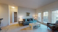 This single-floor residence offers a thoughtfully organized layout that balances comfort and functionality across several well-defined spaces. The living room serves as the heart of the unit, featuring soft carpeting, neutral wall tones, and a pair of glass panel doors that invite abundant natural light and provide outdoor access. A dedicated dining area adjoins the living space, framed by a defined nook with accent wall coloring, offering an intimate setting for meals.

The galley-style kitchen is efficiently arranged with warm wood cabinetry lining both sides, dark granite-style countertops, a double basin sink, and a full suite of black appliances including a range, microwave, and refrigerator. Light hardwood-style flooring runs the length of the kitchen, connecting to a laundry room equipped with a full-size, side-by-side washer and dryer.

Two carpeted bedrooms each feature windows with natural light and ample closet storage. The bathroom is clean and functional, with a full tub and shower combination, wood-style flooring, and a vanity with counter space. Throughout, the unit maintains a cohesive, neutral palette that creates a calm and welcoming atmosphere.