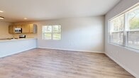 Located at 899 Chapel Dr in Milton, Wisconsin, this three-bedroom, two-bathroom home spans three floors, offering a well-organized and functional layout. The main living level features an open-plan kitchen and living area with durable wood-look LVP flooring and abundant natural light from multiple windows. The kitchen is equipped with stainless steel appliances including a refrigerator, range, and over-the-range microwave, complemented by taupe shaker-style cabinetry, light stone countertops, and a classic subway tile backsplash. A door from the kitchen provides convenient exterior access. The spacious living area is bright and airy, with large windows framing views of the surrounding greenery. The bedrooms are carpeted for comfort, each featuring ceiling fans, natural light from windows with blinds, and ample closet space — including a dedicated walk-in style closet with wood hanging rods and shelving in the primary bedroom. One additional bedroom features a built-in double-door closet and LVP flooring. Both bathrooms are finished with LVP flooring and full tub-shower combinations with brushed nickel fixtures. Two staircases connect the floors, adding ease of circulation throughout this clean, move-in-ready home.