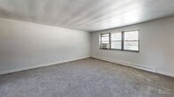 This two-bedroom, one-bathroom residence in Drexel Hill, PA offers a practical and comfortable single-floor layout. The entrance leads into a hallway that connects the living spaces throughout. The spacious living room features soft carpeting, neutral white walls, and windows that invite natural light, creating a bright and airy atmosphere. The kitchen is well-appointed with warm honey-toned wood cabinetry, granite-style countertops, a stone tile backsplash, and black appliances including a gas range, built-in microwave, and dishwasher, all set on clean tile flooring. The generously sized primary bedroom offers plush carpeting, a dedicated closet with built-in shelving, and a window with outdoor views. The second bedroom is similarly carpeted with neutral tones, its own window, and baseboard heating. Both bedrooms provide a calm, understated setting. The bathroom is a standout with retro-inspired mint green ceramic tile walls accented by a dark border, a classic soaking tub, and a mosaic tile floor. With four closets spread throughout the unit, storage is ample. The overall ambiance is clean, neutral, and move-in ready.