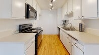 Located at 22555 Nadine Cir in Torrance, California, this single-floor residence offers a well-organized and functional layout with a clean, neutral aesthetic throughout. The galley-style kitchen is equipped with white cabinetry, light countertops, black appliances including an electric range, microwave, and dishwasher, a stainless steel sink, and track lighting overhead — all set atop warm hardwood-style flooring. The kitchen opens toward a dining and living area, where a ceiling fan with a light fixture adds comfort, and the same hardwood-style flooring continues seamlessly. The spacious living room features plush carpeting, bright white walls, a textured ceiling, and a sliding glass door fitted with vertical blinds that allows natural light to fill the room and provides access to an outdoor area. The carpeted bedroom areas offer generous space, with floor-to-ceiling mirrored sliding closet doors framed in gold-tone trim that add a sense of depth and reflect natural light. The bathroom is finished with light wood-style flooring, a long vanity with white cabinetry, and a tub-shower combination with a glass sliding door. Throughout the space, the consistent use of white walls and light finishes creates a bright, cohesive, and move-in-ready environment.
