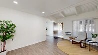 Located at 2301 W La Habra Blvd in La Habra, California, this single-story 2-bedroom, 1-bathroom home offers a well-designed layout across a compact yet efficiently utilized floor plan. The living room is a standout space, showcasing exposed wood beam ceilings with shiplap detailing, recessed lighting, and light wood-look flooring that creates a warm, airy ambiance. Large windows with vertical blinds invite natural light, while a wall-mounted AC unit ensures year-round comfort. The kitchen has been thoughtfully renovated with crisp white shaker cabinetry, quartz countertops, a classic subway tile backsplash, and stainless steel appliances, including a range and built-in microwave. A ceiling fan and an adjacent dining area add to its functionality. Both bedrooms are carpeted and filled with natural light; the primary bedroom features mirrored sliding closet doors that enhance the sense of space. The full bathroom is sleekly appointed with a white vanity, quartz counters, wood-look tile flooring, and a glass-enclosed shower-tub combo. A connecting hallway provides practical flow throughout the home. Two private patios extend the living space outdoors, ideal for relaxing or entertaining in the Southern California climate.