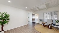 Located at 2301 W La Habra Blvd in La Habra, California, this single-story 2-bedroom, 1-bathroom home offers a well-designed layout across a compact yet efficiently utilized floor plan. The living room is a standout space, showcasing exposed wood beam ceilings with shiplap detailing, recessed lighting, and light wood-look flooring that creates a warm, airy ambiance. Large windows with vertical blinds invite natural light, while a wall-mounted AC unit ensures year-round comfort. The kitchen has been thoughtfully renovated with crisp white shaker cabinetry, quartz countertops, a classic subway tile backsplash, and stainless steel appliances, including a range and built-in microwave. A ceiling fan and an adjacent dining area add to its functionality. Both bedrooms are carpeted and filled with natural light; the primary bedroom features mirrored sliding closet doors that enhance the sense of space. The full bathroom is sleekly appointed with a white vanity, quartz counters, wood-look tile flooring, and a glass-enclosed shower-tub combo. A connecting hallway provides practical flow throughout the home. Two private patios extend the living space outdoors, ideal for relaxing or entertaining in the Southern California climate.