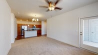 This single-floor residence offers a thoughtfully designed open-concept layout that seamlessly connects the living and kitchen areas. The spacious living room features neutral carpet, a ceiling fan with integrated lighting, and generous wall space, creating a versatile and comfortable environment. A chandelier overhead adds a refined touch to the shared living and dining space.

The kitchen is a standout feature, showcasing warm-toned wood cabinetry that extends to the ceiling, light granite countertops, and stainless steel appliances including a refrigerator, electric range, and built-in microwave. A large center island with a sink and matching granite surface provides additional workspace and seating, illuminated by pendant lighting above. Hardwood-style flooring grounds the kitchen and flows throughout the non-carpeted areas.

The bathrooms feature matching wood vanities with granite countertops, hardwood-style flooring, and clean, neutral finishes. The primary bathroom includes a double-sink vanity and direct access to a walk-in closet equipped with wire shelving systems for organized storage. Additional bedrooms offer carpet flooring and windows that invite natural light. The overall ambiance is clean, cohesive, and move-in ready.