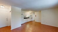 Located at 119-125 S Park Ridge Rd in Bloomington, Indiana, this one-bedroom, one-bathroom unit offers a practical and comfortable single-floor layout. The kitchen is equipped with ample white cabinetry extending to the ceiling, dark granite-style countertops, a full suite of white appliances including a refrigerator, dishwasher, and range, and warm wood-style flooring that flows into the adjoining living area. Crown molding adds a clean, finished touch throughout the kitchen and living spaces. The living room is bright and open, featuring a window that allows natural light to filter in alongside views of surrounding greenery, and is served by a baseboard heating system. The bedroom is carpeted for comfort, fitted with a ceiling fan with light fixture, a reach-in closet, and its own window overlooking the outdoors. The full bathroom includes a tub and shower combination with a surrounding surround enclosure. The unit's neutral color palette, consistent finishes, and efficient layout make it a functional and inviting living space well-suited for those seeking a manageable, low-maintenance home in Bloomington.