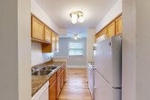 Located at 6725 N Sheridan Road in Chicago's Rogers Park neighborhood, this one-bedroom, one-bathroom unit offers a practical and well-organized layout across a single floor. Warm hardwood floors run throughout the space, lending a cohesive and inviting feel to every room.

A long entry hallway connects the main living areas, with the galley-style kitchen positioned conveniently off the corridor. The kitchen features warm wood cabinetry extending to the ceiling for generous storage, granite-style countertops, a stainless steel sink, and white appliances including a refrigerator and range. A window at the far end brings in natural light and overlooks the dining area, which is outfitted with a ceiling fan.

The open living and dining areas are bright and airy, with large windows allowing natural light to fill the space. The living room is generously proportioned for the bedroom count, offering ample room for a variety of furniture arrangements.

The bedroom is a comfortable size, featuring hardwood floors, a window with blinds, a wall-unit air conditioner, and mirrored sliding closet doors. Notably, the unit includes six closets in total, providing exceptional storage throughout.

The neutral gray wall tones and clean white trim create a modern, move-in-ready aesthetic throughout the entire unit.