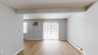 Located at 1700 Newcombtown Rd in Millville, NJ, this single-floor unit offers a well-designed layout with a clean, neutral aesthetic throughout. The spacious living area is finished with warm light wood-tone flooring and painted in soft gray and white tones, creating a bright and welcoming atmosphere. Large vertical-blind-covered sliding glass doors allow natural light to fill the space, while baseboard heating and a wall-mounted AC unit provide year-round climate control. The open layout connects the living area seamlessly to the kitchen, which is a standout feature of the unit. Dark espresso-toned cabinetry is paired with white countertops, a white subway tile backsplash, and a full suite of stainless steel appliances, including a refrigerator, range, and dishwasher. A peninsula counter provides additional workspace and a natural division between the kitchen and living areas. The bedroom offers plush carpeting, a bright window with a privacy blind, and baseboard heating. The bathrooms are finished with white subway tile wainscoting, a full tub-shower combination, and clean white fixtures, maintaining a consistent and practical design throughout the unit.