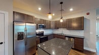 Located at 541 Clancy Ave NE in Grand Rapids, Michigan, this single-floor residence offers a thoughtfully designed layout with quality finishes throughout. The kitchen serves as the heart of the home, showcasing rich dark wood cabinetry, deep granite countertops, and a full suite of stainless steel appliances including a refrigerator with ice maker, electric range, built-in microwave, and dishwasher. A central island with matching granite provides additional prep and dining space, while subway tile backsplash and dual pendant lights lend a contemporary aesthetic. Warm hardwood-style flooring flows throughout the main living and kitchen areas, adding visual continuity and a sense of warmth. The bedrooms are carpeted and bathed in natural light from multiple windows fitted with blinds, offering a comfortable and quiet retreat. Two full bathrooms feature earthy stone-look tile flooring and dark wood vanities. One bathroom includes a dedicated walk-in shower, while the other offers a full tub-shower combination. Clean neutral wall tones and crisp white trim throughout create a cohesive, move-in-ready atmosphere that balances modern upgrades with everyday functionality.