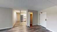 This single-floor unit offers a thoughtfully designed layout with a clean, contemporary aesthetic throughout. The open living area is a standout feature, showcasing durable hardwood-style flooring in a cool grey tone, neutral walls, and a textured ceiling. A sliding glass door leads to a private balcony, allowing natural light to fill the space and offering pleasant outdoor views of surrounding greenery.

The kitchen is a highlight of the unit, featuring crisp white shaker-style cabinetry, marble-look countertops, and a full suite of stainless steel appliances including a refrigerator, dishwasher, electric range, and microwave. Light wood-style flooring and recessed lighting give the kitchen a bright, modern feel.

The bedroom provides a comfortable retreat with plush carpeting, a generously sized closet, and a sliding glass door that opens to a balcony. A built-in wall unit and easy access to an adjoining bathroom add to the room's functionality.

Two bathrooms serve the unit, each featuring a tiled tub-shower combination. One bathroom is updated with a white vanity, wood-style flooring, and modern chrome fixtures, while the other offers a classic white tile surround. Convenient in-unit closet storage is also available, rounding out this practical and well-maintained space.