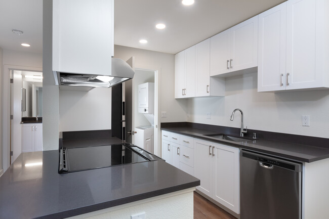 Kitchen with white cabinetry, stainless steel appliances, dark grey countertops and hard surface flooring - eaves Fremont