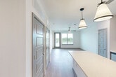Located at 2424 Elam Ln in Chattanooga, TN, this well-appointed one-bedroom, one-bathroom unit offers a thoughtfully designed single-floor layout with modern finishes throughout. The open-concept kitchen and living area serves as the heart of the home, featuring a large center island with quartz countertops, sleek gray cabinetry, a white geometric tile backsplash, and a full suite of stainless steel appliances including a range, microwave, refrigerator, and dishwasher. Stylish pendant lighting illuminates the island, while recessed lighting brightens the kitchen. Light wood-tone flooring extends through the main living areas, lending a clean, contemporary feel. The living room opens directly to a private balcony through a glass door, allowing natural light to pour in alongside outdoor views. A ceiling fan adds comfort to the space. The bedroom is finished with plush carpet, a ceiling fan, and a window with outdoor views. The bathroom is a standout feature, offering a double-sink vanity with blue-gray cabinetry, black hardware, quartz countertops, framed mirrors, and a tiled walk-in shower. Additional spaces include a dedicated office, a laundry area, and two closets, providing ample storage and functional flexibility throughout.