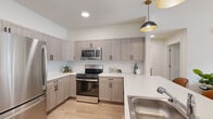 Located at 1990 Rimel Rd in Missoula, Montana, this thoughtfully designed 2-bedroom, 2-bathroom residence offers a clean, modern aesthetic across a well-organized single-floor layout. Light wood-look flooring runs throughout the main living areas, tying together the open-concept kitchen, dining, and living spaces. The kitchen is a standout feature, equipped with stainless steel appliances including a gas range, over-the-range microwave, and full-size refrigerator. Warm-toned wood-grain cabinetry extends from floor to ceiling, complemented by crisp white countertops, a tile backsplash, and stylish pendant lighting overhead. The living room is bright and welcoming, anchored by a large sliding glass door that opens to an outdoor patio and fills the space with natural light. Both bedrooms are comfortably sized, with the primary bedroom offering a double-door closet and plush carpet flooring. Each bedroom benefits from its own ceiling fan or window for ventilation and comfort. The two bathrooms mirror the kitchen's design language, featuring matching wood-grain vanities, white countertops, and light tile flooring. One bathroom includes a full soaking tub with shower combination. Hallways connect each area efficiently, with a dedicated closet providing additional storage. The overall ambiance is calm, contemporary, and functional.