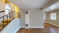 Located at Santa Clara Street in Hayward, California, this single-floor unit offers a practical and well-organized layout with a variety of functional spaces. The living area is generously sized, featuring warm hardwood-style flooring that extends throughout the main areas. A large sliding glass door floods the room with natural light while providing access to the outdoors, complemented by an additional window that enhances the bright, open feel. A staircase with a black metal railing adds a subtle architectural detail, with a vertical HVAC unit positioned nearby for climate control.

The galley-style kitchen is efficiently designed with white cabinetry lining both sides, dark stone countertops, a stainless steel sink with a modern faucet, and stainless steel appliances including a range and refrigerator. The light wood flooring continues here, maintaining visual continuity.

The bedrooms are carpeted in a neutral tone and receive natural light through slatted blinds. One bedroom includes a sliding closet with built-in shelving. The bathroom features hardwood-style flooring, a white vanity with a dark countertop, and a tiled tub-shower combination. Throughout, the unit maintains a neutral, taupe-toned color palette that creates a calm, cohesive ambiance.