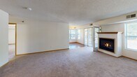 Located at 1045 Yellow Brick Rd in Chaska, Minnesota, this single-floor unit offers a well-organized layout with a variety of functional living spaces. The expansive living room is a standout feature, showcasing plush carpeting, a wood-mantled fireplace, and large sliding patio doors flanked by windows that invite abundant natural light and provide access to an outdoor area. The kitchen is well-appointed with warm oak cabinetry, ample counter space, hardwood flooring, and black appliances including a range and refrigerator, complemented by a double sink beneath a window. Multiple carpeted rooms serve as comfortable bedrooms, each featuring windows with outdoor views, six-panel wood doors, and textured ceilings. The unit includes two bathrooms finished with white tile flooring, oak vanities with light countertops, and brushed nickel fixtures. One bathroom features a full tub/shower combination, while the other is a spacious three-quarter bath with grab bars. Throughout the unit, consistent neutral-toned walls, wood baseboards, and textured ceilings contribute to a clean, cohesive aesthetic suited for comfortable everyday living.