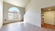 Located in Fairview, Oregon, this two-story, three-bedroom, two-bathroom home offers a well-designed layout across two floors. The main level immediately impresses with soaring vaulted ceilings and a striking arched window that floods the living area with natural light, complemented by durable light-toned hardwood-style flooring. The kitchen is thoughtfully appointed with stainless steel appliances including an electric range, microwave, and refrigerator, warm wood cabinetry, a clean white countertop with an integrated sink, and open built-in shelving for added storage. A dedicated in-unit laundry area with a stacked washer and dryer is conveniently accessible from the kitchen. The two bathrooms are clean and modern; the primary bath features a dual-sink vanity with rich wood cabinetry and a large mirror, while the secondary bath includes a single-sink vanity with matching finishes and a shower-tub combination. All three bedrooms are carpeted for comfort, offering natural light through window blinds and ample closet space with sliding doors. The generously sized primary bedroom includes a walk-in-style closet. Neutral tones and clean finishes throughout create a bright, cohesive ambiance suited for comfortable everyday living.