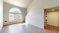 Located in Fairview, Oregon, this two-story, three-bedroom, two-bathroom home offers a well-designed layout across two floors. The main level immediately impresses with soaring vaulted ceilings and a striking arched window that floods the living area with natural light, complemented by durable light-toned hardwood-style flooring. The kitchen is thoughtfully appointed with stainless steel appliances including an electric range, microwave, and refrigerator, warm wood cabinetry, a clean white countertop with an integrated sink, and open built-in shelving for added storage. A dedicated in-unit laundry area with a stacked washer and dryer is conveniently accessible from the kitchen. The two bathrooms are clean and modern; the primary bath features a dual-sink vanity with rich wood cabinetry and a large mirror, while the secondary bath includes a single-sink vanity with matching finishes and a shower-tub combination. All three bedrooms are carpeted for comfort, offering natural light through window blinds and ample closet space with sliding doors. The generously sized primary bedroom includes a walk-in-style closet. Neutral tones and clean finishes throughout create a bright, cohesive ambiance suited for comfortable everyday living.