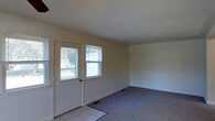 This two-floor home offers a straightforward and functional layout designed for comfortable everyday living. The entryway greets visitors with tile flooring and a classic paneled front door flanked by windows that invite an abundance of natural light into the space. Just beyond the entry, the main living area transitions to wall-to-wall carpeting, creating a warm and comfortable atmosphere. The walls are finished in a clean, neutral tone throughout, providing a versatile backdrop suited to a variety of interior styles. The windows are fitted with blinds, offering practical light control while maintaining a tidy appearance. Flush with the wall, floor vents indicate a forced-air climate system to keep the home comfortable year-round. The open feel of the main level is enhanced by smooth ceilings and simple, uncluttered lines that give the space a bright and airy quality. Spanning two floors, the home provides a clear separation between living and private spaces, with the upper level offering additional room for bedrooms or auxiliary uses. Overall, the property presents a clean, move-in ready environment with timeless, understated finishes throughout.